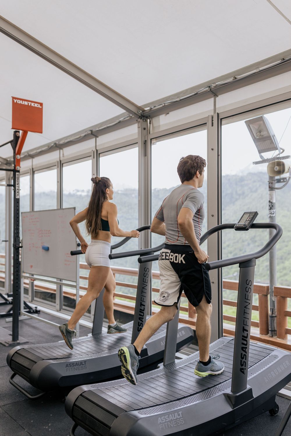 Runners on curved treadmills in a glass-walled gym
