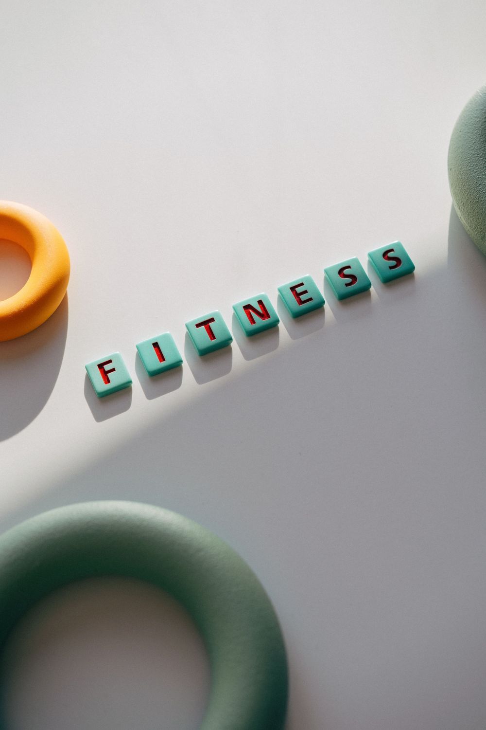Letter tiles spelling fitness beside colourful grip rings
